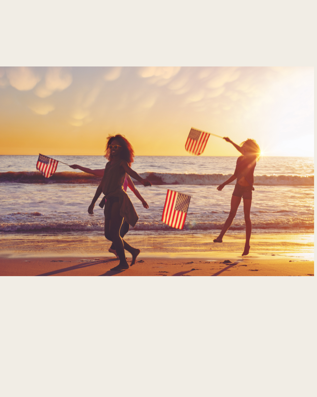 Dos personas en la playa con banderas estadounidenses al atardecer — 4 de julio en Tampa, FL